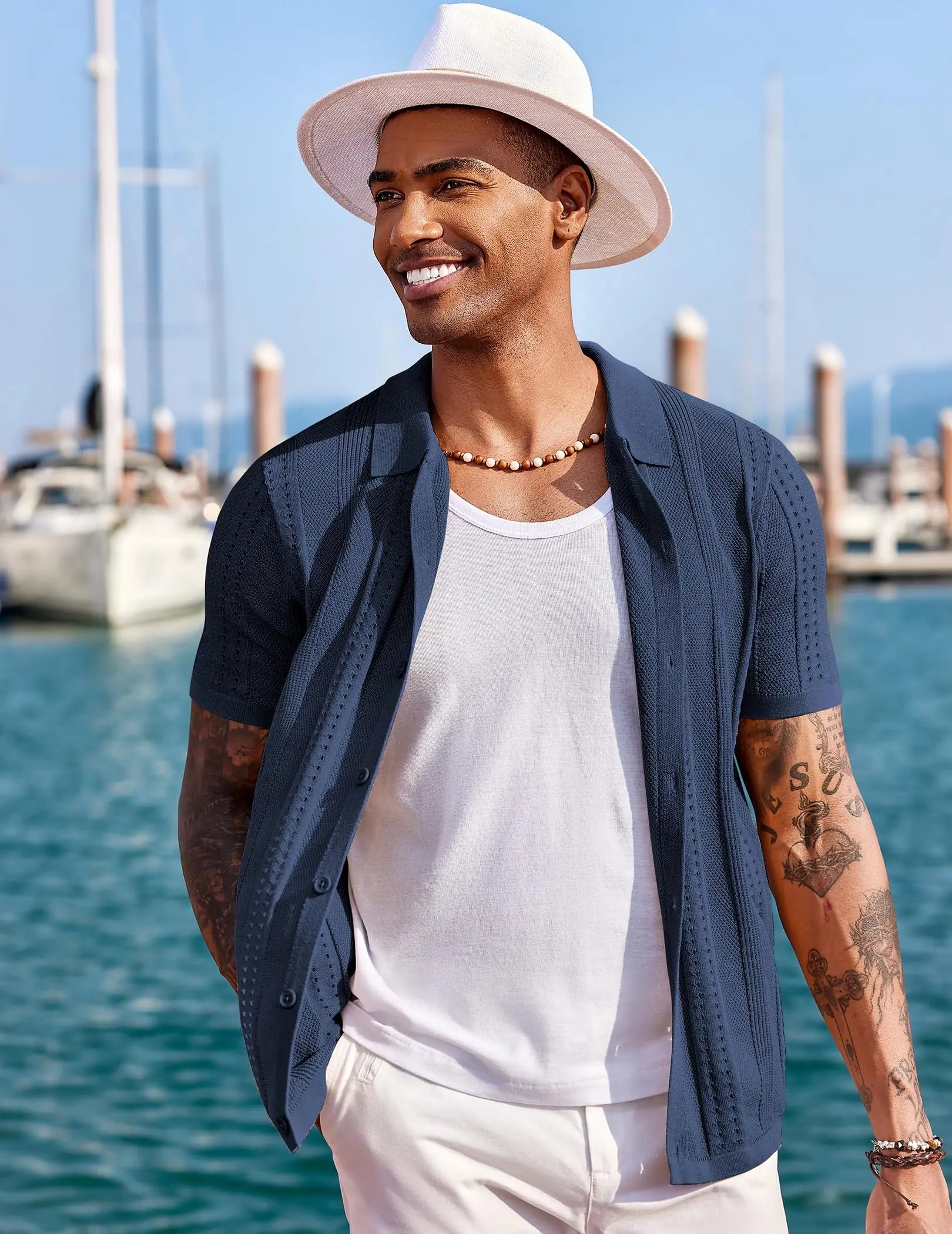 Chemise en maille bleu marine portée ouverte sur un débardeur blanc dans une marina